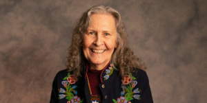 A photo of beadwork artist Jennine Krauchi, smiling at the camera.