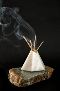 A soapstone carving of a tipi. Smoke rises from its top.
